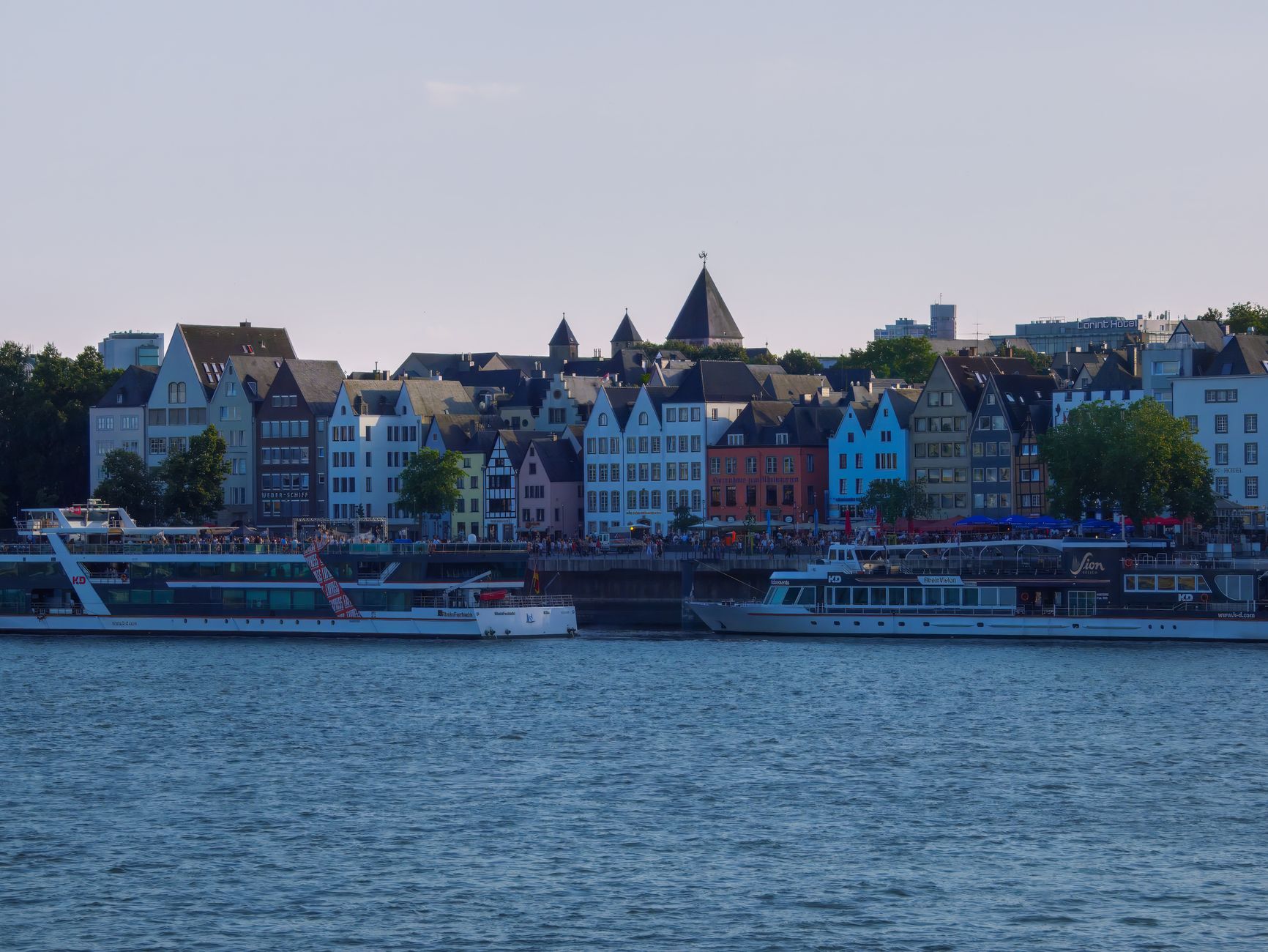 Charming waterfront view with colorful buildings and boats on the Rhine River.